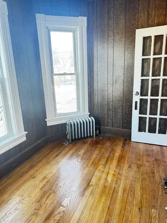 a view of an empty room with a window and wooden floor