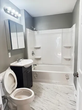 a bathroom with a sink a toilet a mirror and bathtub