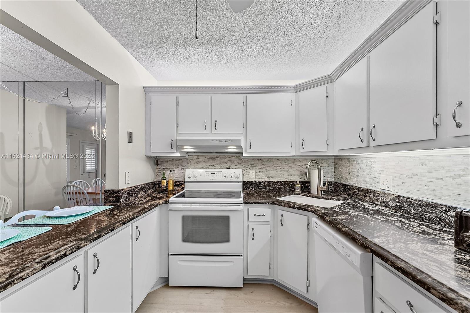 341 Pine Ridge Circle, Unit B2 Greenacres, FL 33463 - Photo 18 of 49 a kitchen with granite countertop white cabinets and white appliances