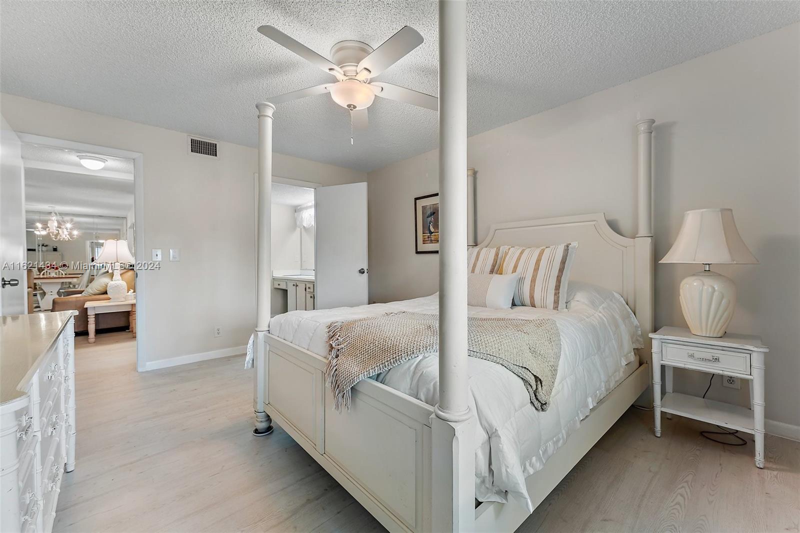 341 Pine Ridge Circle, Unit B2 Greenacres, FL 33463 - Photo 24 of 49 a spacious bedroom with a bed and a chandelier