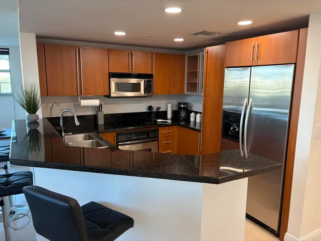 a kitchen with stainless steel appliances granite countertop a refrigerator a stove a sink and a microwave