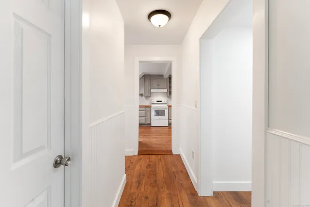 a view of a hallway with wooden floor and a bathroom