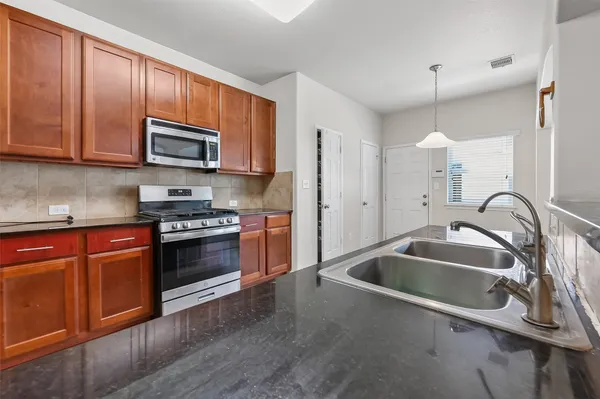 a kitchen with stainless steel appliances granite countertop a sink and a stove top oven with wooden floor