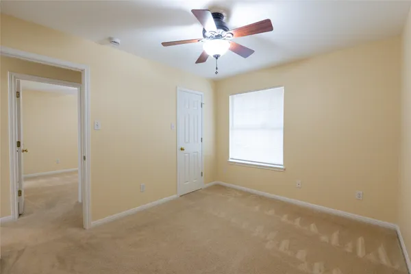 an empty room with a chandelier fan and windows