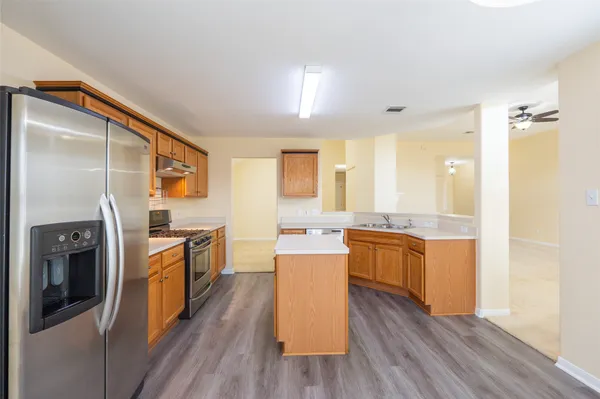 a kitchen with stainless steel appliances granite countertop a refrigerator a stove top oven and sink