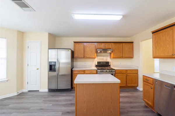 a kitchen with stainless steel appliances a stove a refrigerator a sink a oven with wooden floor