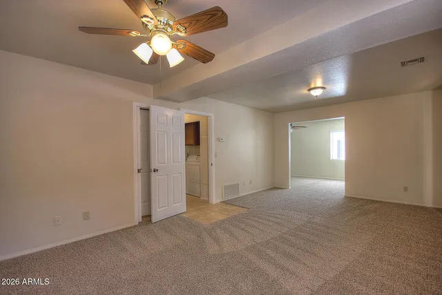 a view of an empty room and chandelier fan