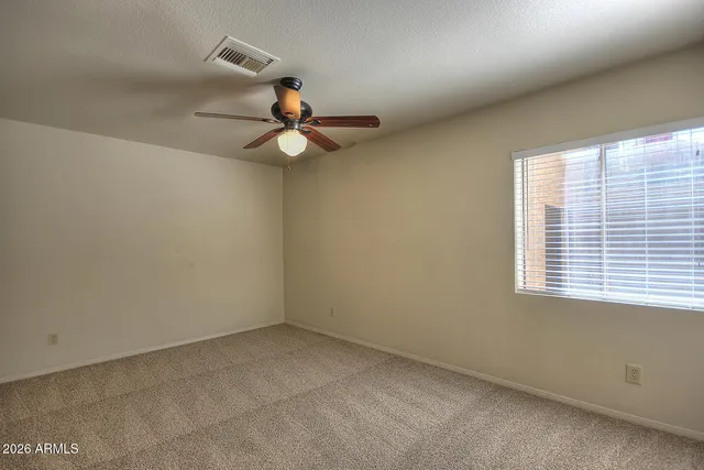 an empty room with a window and a fan