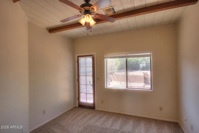 an empty room with windows and chandelier fan
