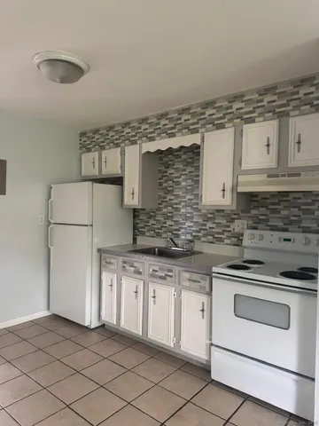 a kitchen with granite countertop white cabinets and white appliances