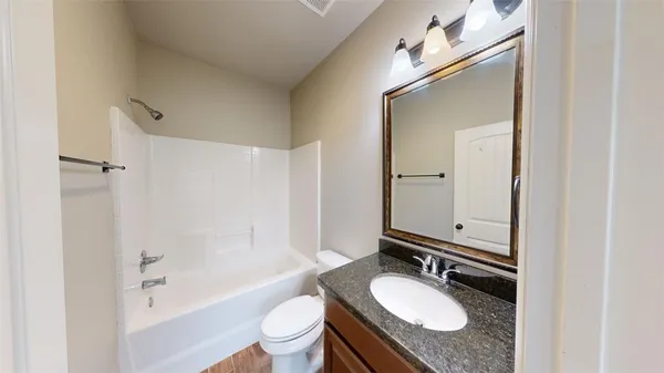 a bathroom with a granite countertop sink toilet mirror and bathtub