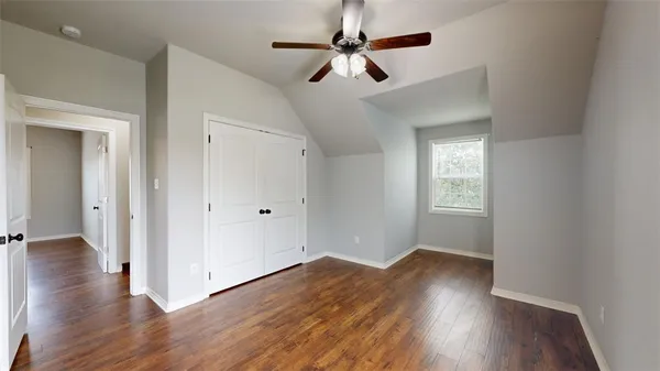 an empty room with wooden floor fan and windows