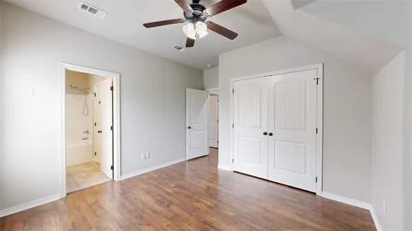 an empty room with wooden floor ceiling fan and windows