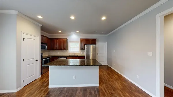 a kitchen with kitchen island granite countertop a refrigerator and a stove
