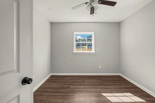 a view of an empty room with wooden floor and a window