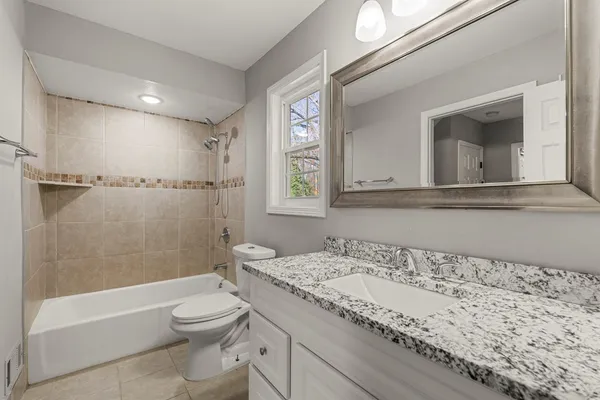 a bathroom with a granite countertop sink a toilet and bathtub