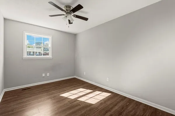 an empty room with wooden floor and windows