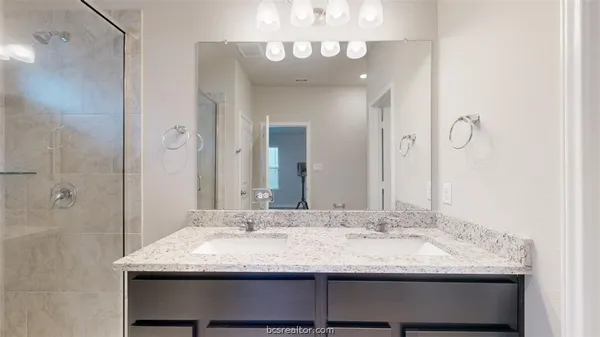 a bathroom with a granite countertop sink a mirror and a shower