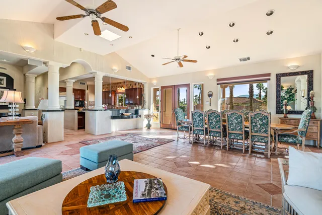 a living room with furniture kitchen view and a large window