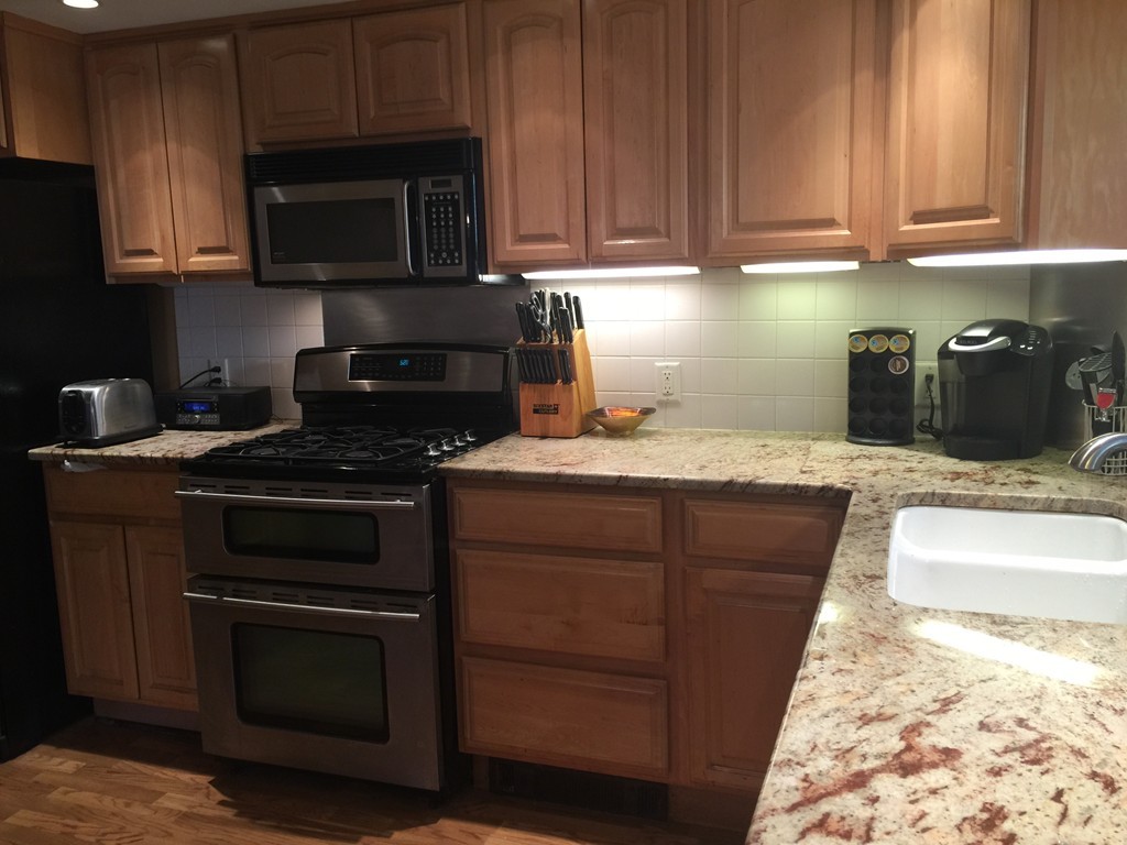 30 Tinson Road Quincy, MA 02169 - Photo 6 of 10 a kitchen with granite countertop wooden cabinets and a stove top oven