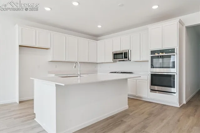 a kitchen with stainless steel appliances granite countertop a stove a sink and a microwave