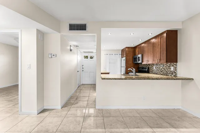 a view of a kitchen with kitchen island granite countertop a refrigerator and a sink