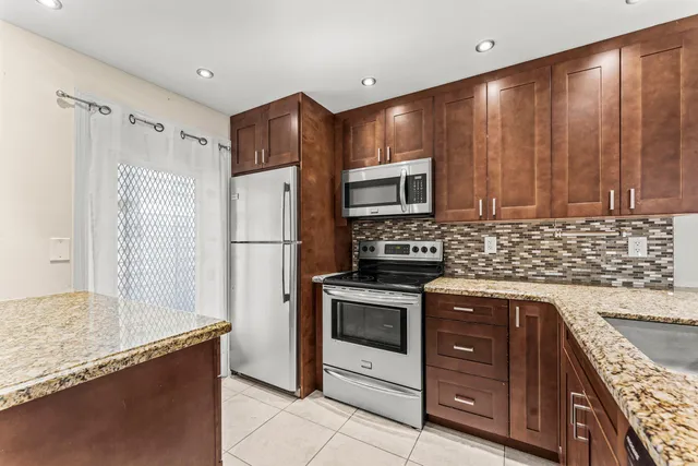 a kitchen with granite countertop wooden cabinets and stainless steel appliances