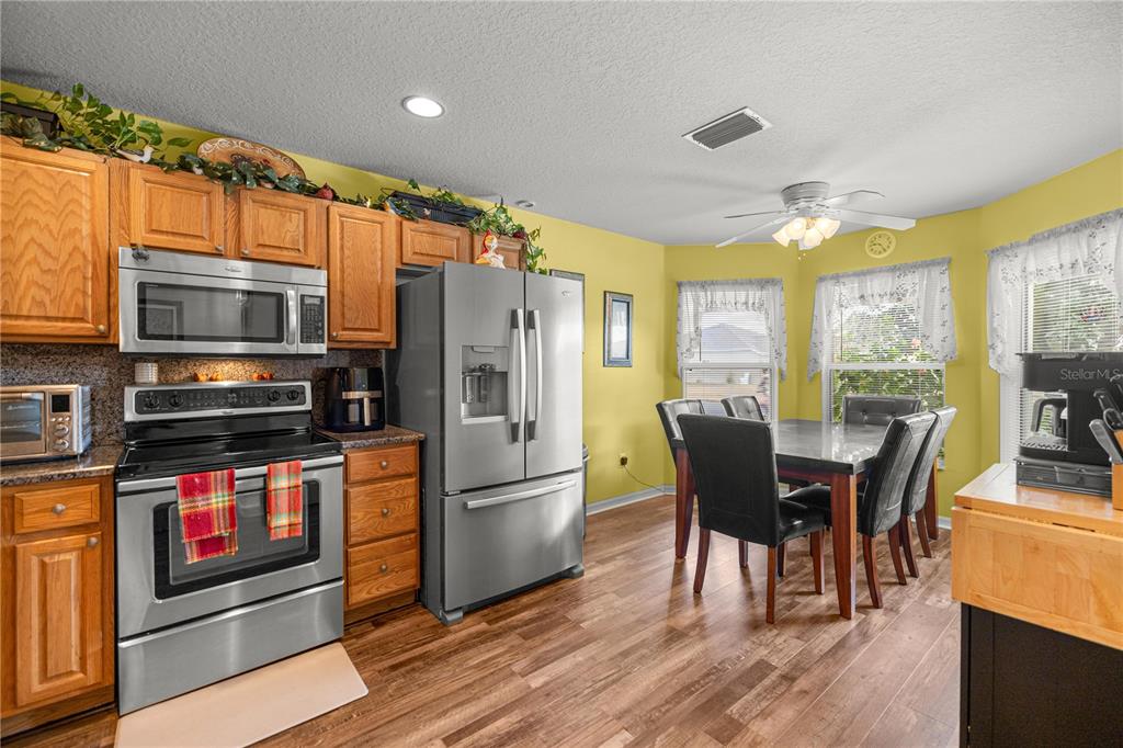 15771 Southwest 13th Circle Ocala, FL 34473 - Photo 7 of 29 a kitchen with stainless steel appliances granite countertop a stove a refrigerator a kitchen island a dining table and chairs