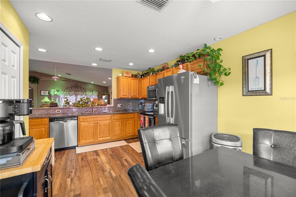 15771 Southwest 13th Circle Ocala, FL 34473 - Photo 9 of 29 a kitchen with stainless steel appliances granite countertop a refrigerator a sink dishwasher and wooden cabinets with wooden floor