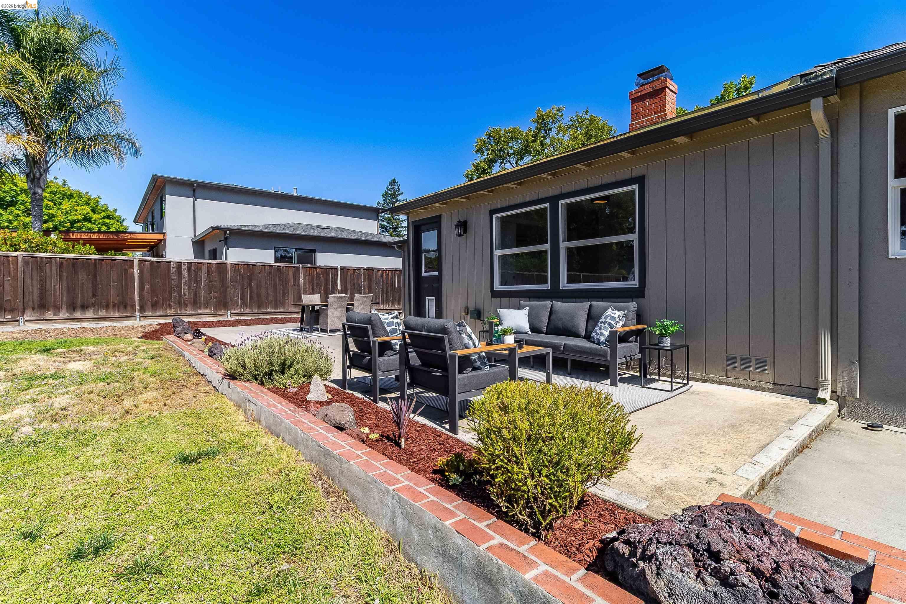 346 Valley View Road Pleasant Hill, CA 94523 - Photo 41 of 57 Rear exterior featuring a concrete patio, board and batten siding, multiple windows, and a brick chimney