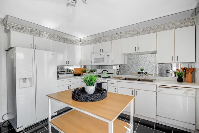 a kitchen with stainless steel appliances a white table chairs and a refrigerator