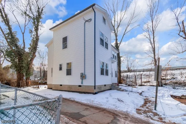 a view of a white house with a large tree