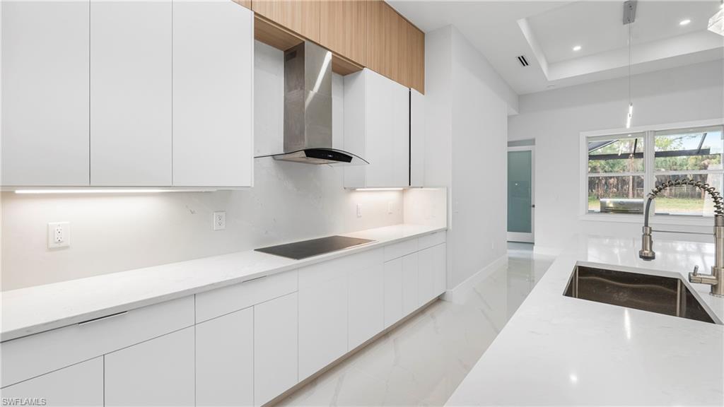 1687 19th Street Southwest Naples, FL 34117 - Photo 8 of 50 Kitchen featuring decorative light fixtures, light stone countertops, modern cabinets, light marble finish flooring, and a center island with sink