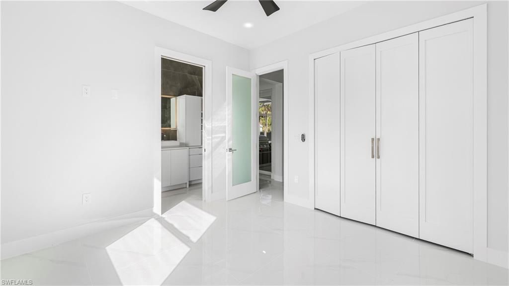 1687 19th Street Southwest Naples, FL 34117 - Photo 18 of 50 Unfurnished bedroom featuring a ceiling fan, a closet, ensuite bathroom, light marble finish floors, and recessed lighting