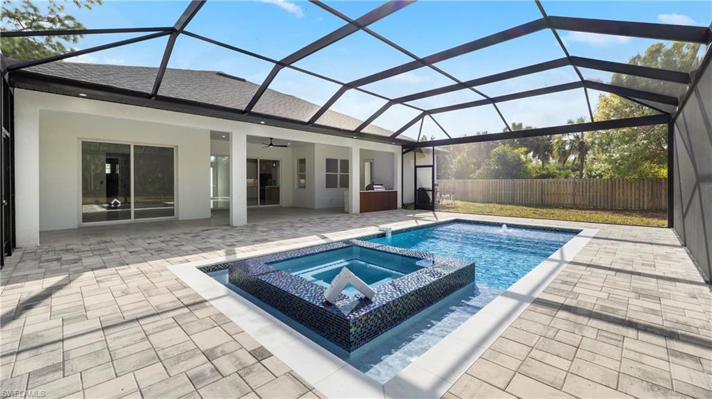 1687 19th Street Southwest Naples, FL 34117 - Photo 33 of 50 View of pool featuring a sunroom, glass enclosure, a pool with connected hot tub, and a patio