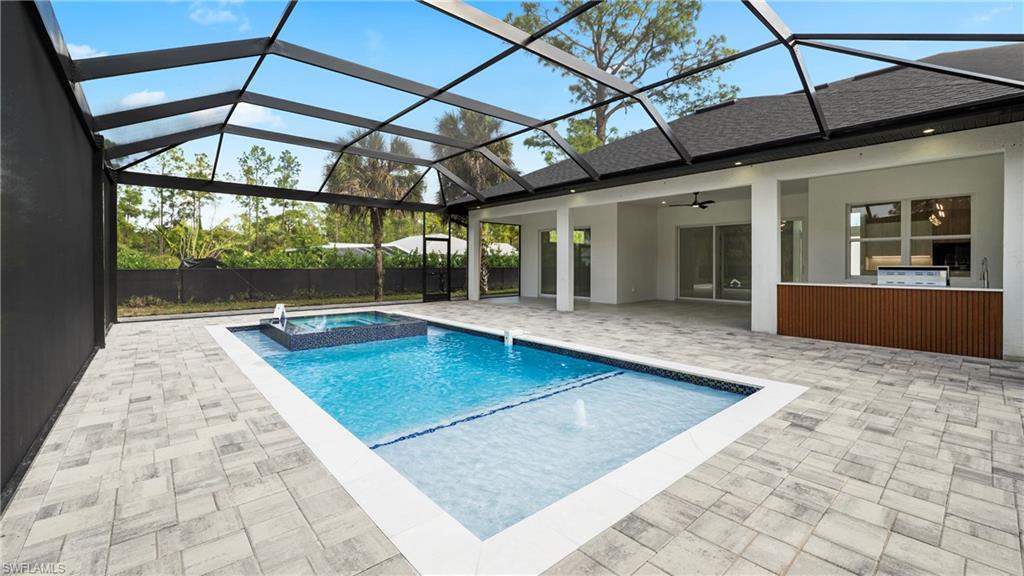 1687 19th Street Southwest Naples, FL 34117 - Photo 34 of 50 View of pool featuring a sunroom, glass enclosure, a patio area, and a pool with connected hot tub