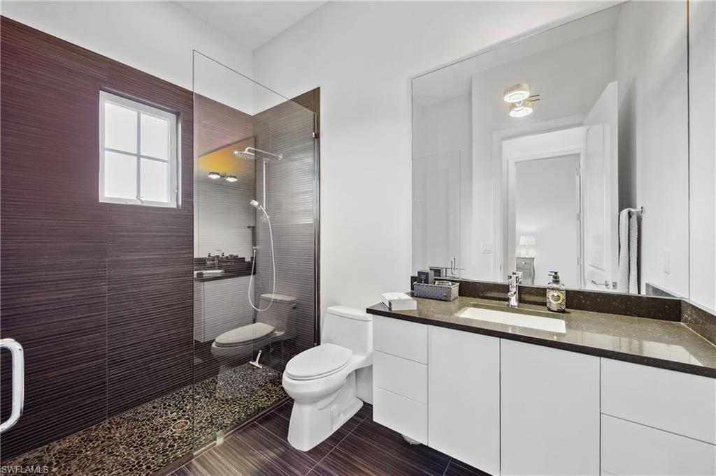 299 Mermaids Bight Naples, FL 34103 - Photo 19 of 28 a bathroom with a granite countertop toilet sink and mirror