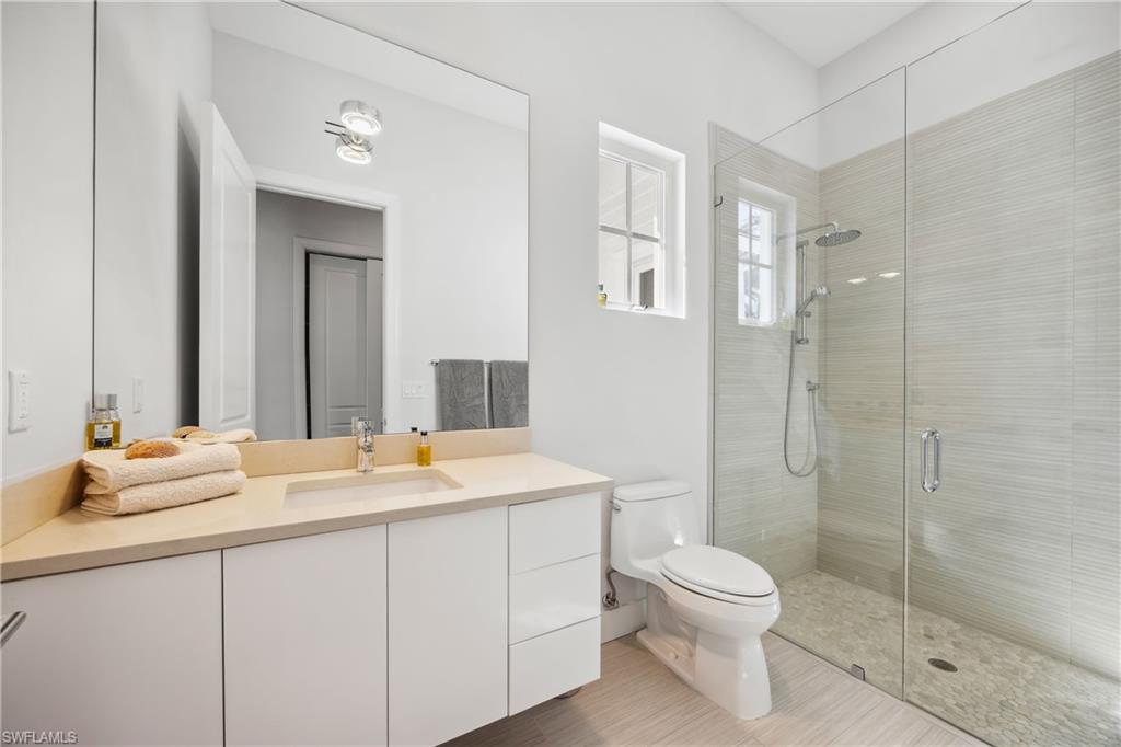 299 Mermaids Bight Naples, FL 34103 - Photo 22 of 28 a bathroom with a granite countertop sink toilet a large mirror a shower and a bathtub