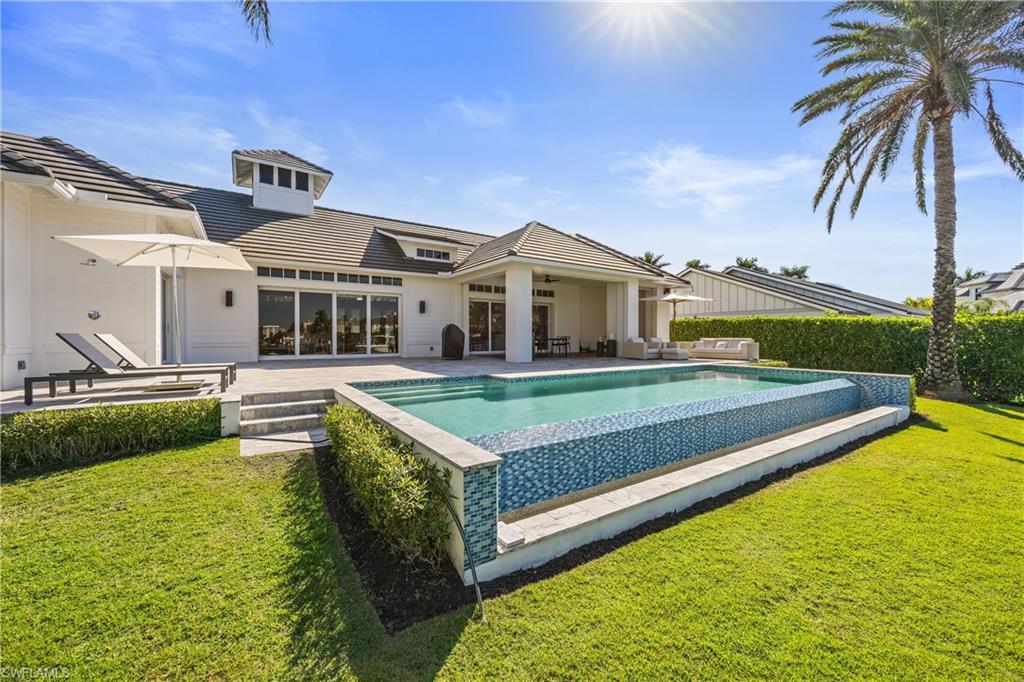 299 Mermaids Bight Naples, FL 34103 - Photo 4 of 28 a view of a house with swimming pool and a yard