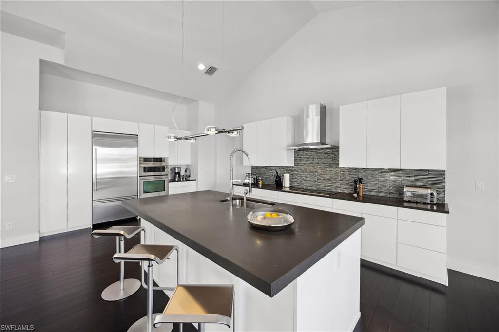 299 Mermaids Bight Naples, FL 34103 - Photo 7 of 28 a kitchen with kitchen island granite countertop a sink appliances and cabinets
