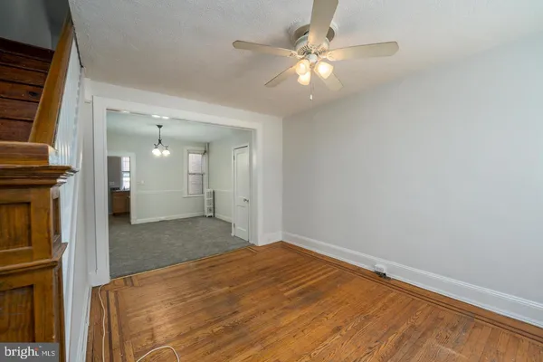an empty room with chandelier fan and windows