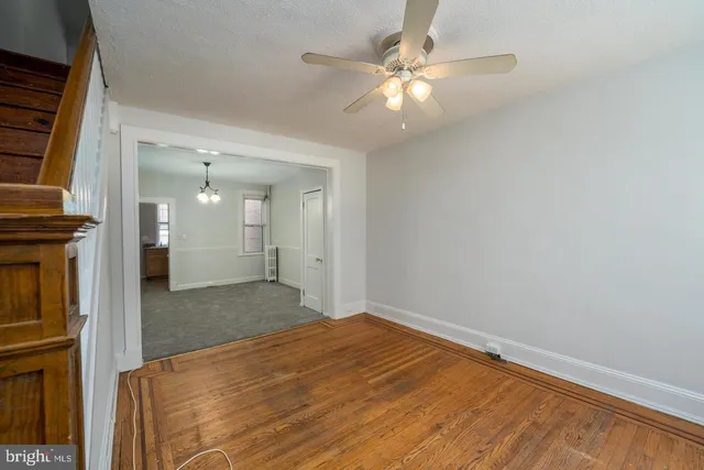 an empty room with chandelier fan and windows