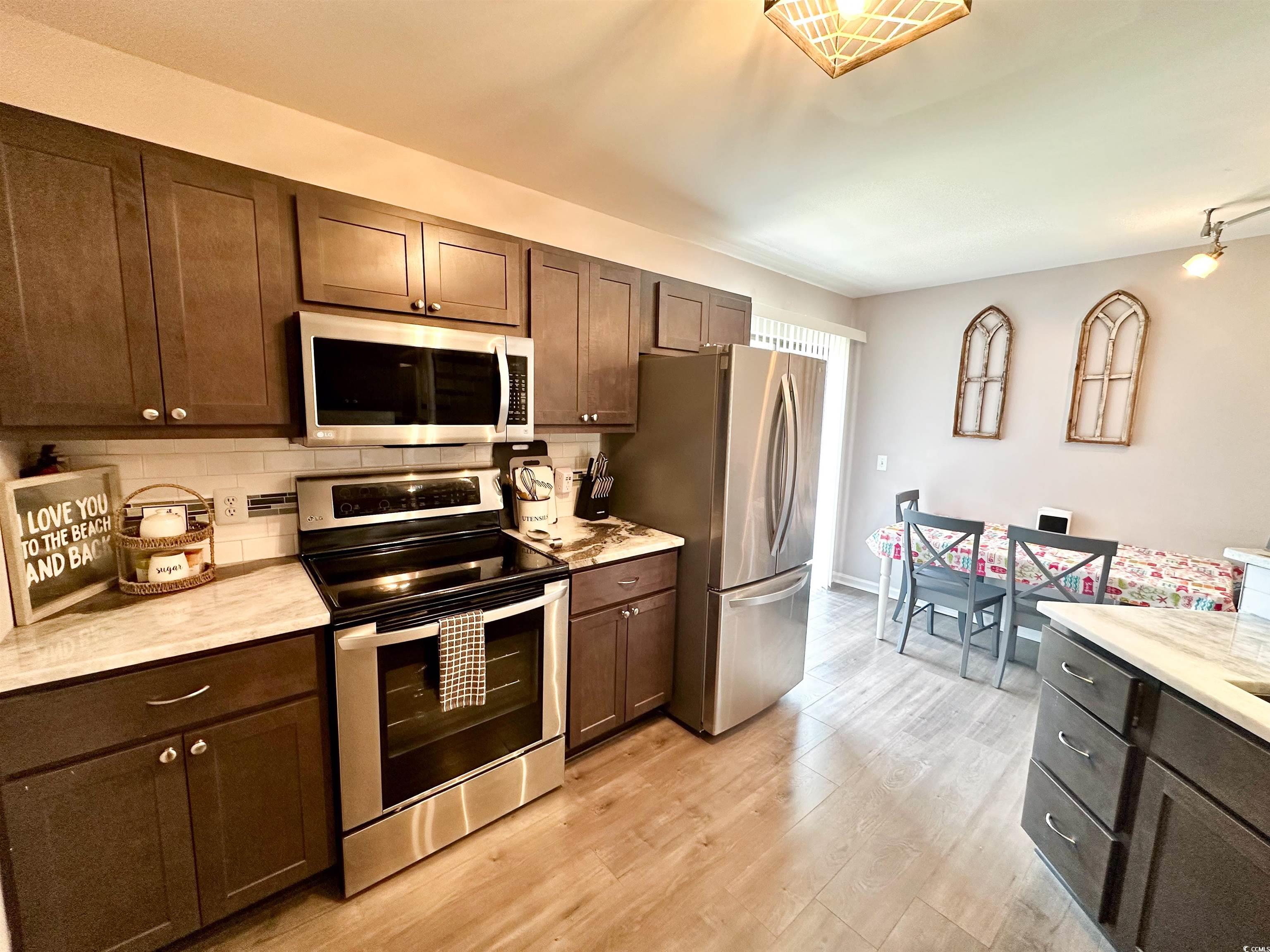 1356 Glenns Bay Road, Unit C202 Surfside Beach, SC 29575 - Photo 9 of 35 Kitchen with stainless steel appliances, backsplash, dark brown cabinetry, and light stone counters