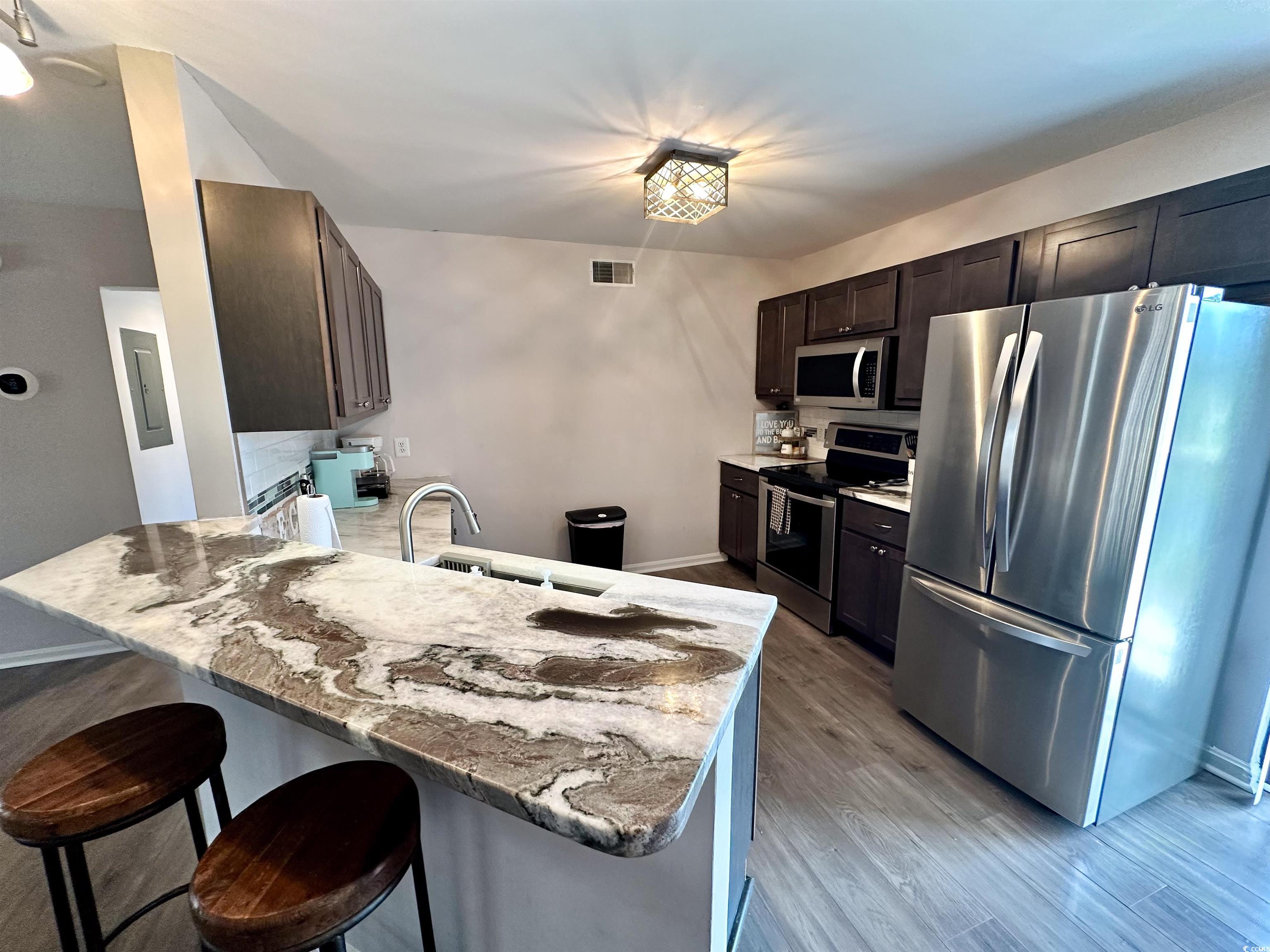 1356 Glenns Bay Road, Unit C202 Surfside Beach, SC 29575 - Photo 11 of 35 Kitchen featuring dark brown cabinets, a peninsula, backsplash, and stainless steel dishwasher