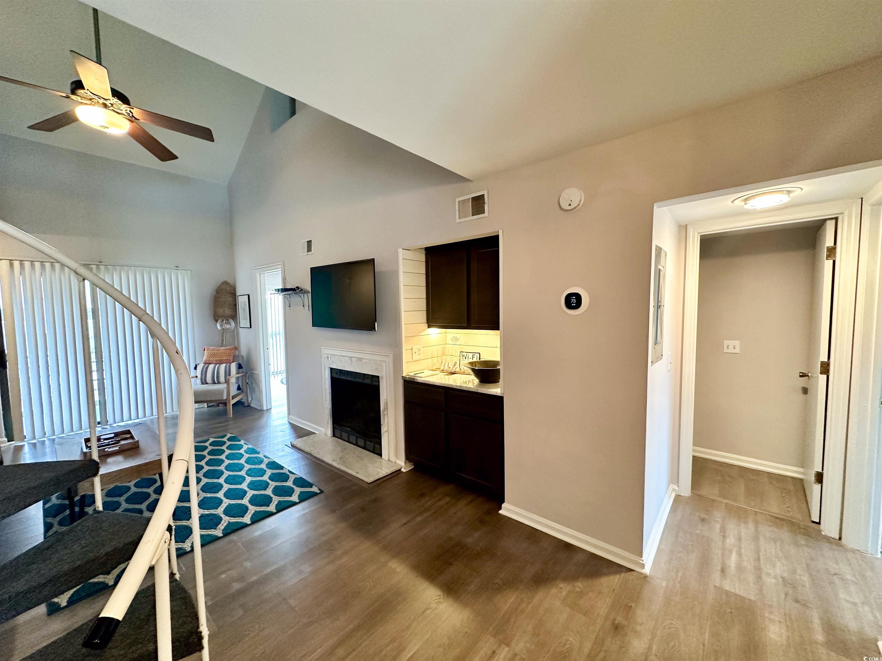 1356 Glenns Bay Road, Unit C202 Surfside Beach, SC 29575 - Photo 4 of 35 Living area with stairway, dark wood finished floors, ceiling fan, a high end fireplace, and a towering ceiling