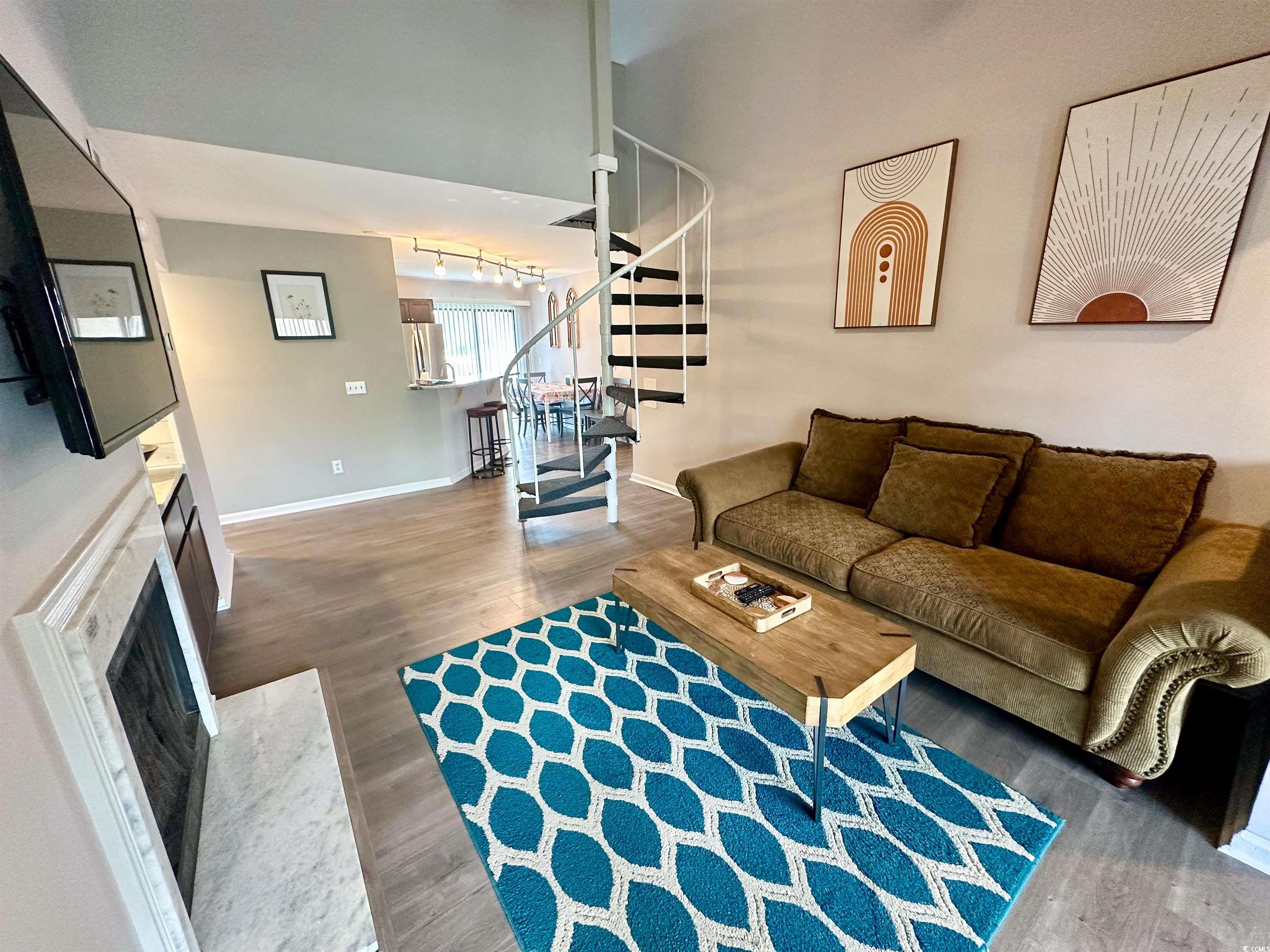 1356 Glenns Bay Road, Unit C202 Surfside Beach, SC 29575 - Photo 6 of 35 Living area featuring wood finished floors, vaulted ceiling, stairs, a ceiling fan, and a fireplace