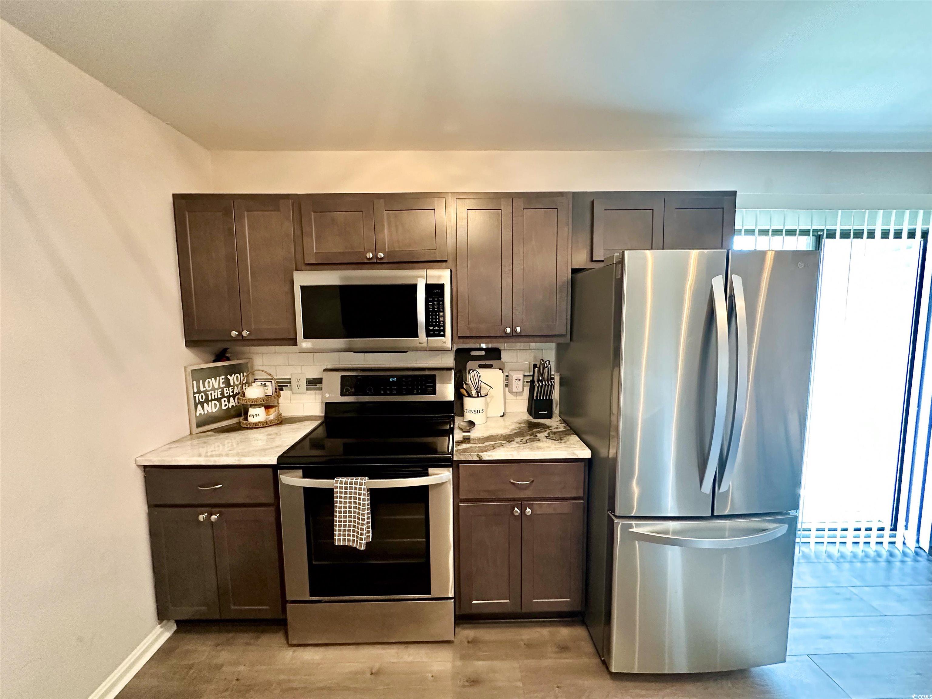 1356 Glenns Bay Road, Unit C202 Surfside Beach, SC 29575 - Photo 35 of 35 Kitchen featuring a peninsula, dark brown cabinetry, open floor plan, dark wood-style floors, and dishwasher