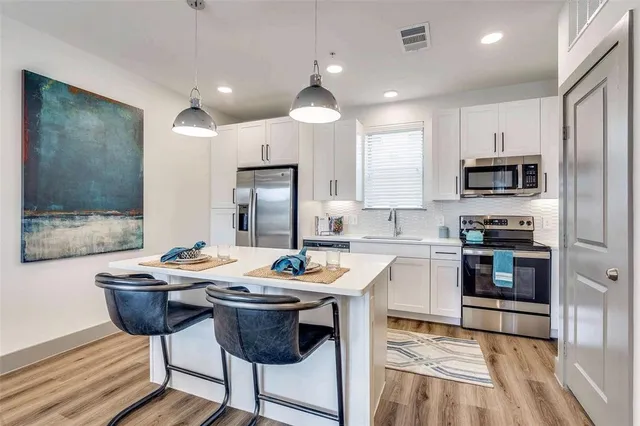 a kitchen with stainless steel appliances kitchen island granite countertop a sink stove and refrigerator