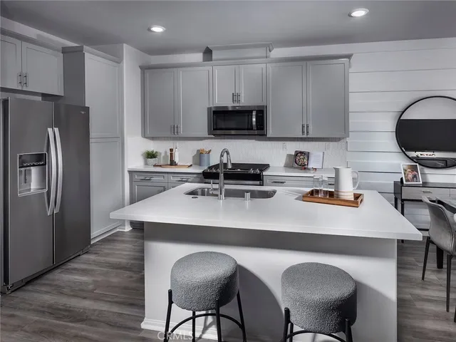 a kitchen with stainless steel appliances a sink a stove a refrigerator cabinets and chairs