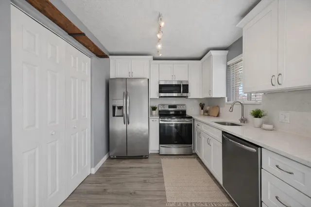 a kitchen with stainless steel appliances granite countertop a refrigerator a stove top oven a sink and dishwasher